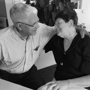 Kuvassa puusepänliike Taitopuun emeritusyrittäjät Simo ja Vuokko Vesamäki puolihalaavat, katsovat toisiaan silmiin, hymyilevät ja salaisuutena kerrottakoon; salamavalon sammuttua suutelevat !
